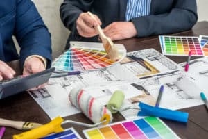 Two engineer discussing apartament blueprints working at chosing color on pallete and laptop. creative workplace